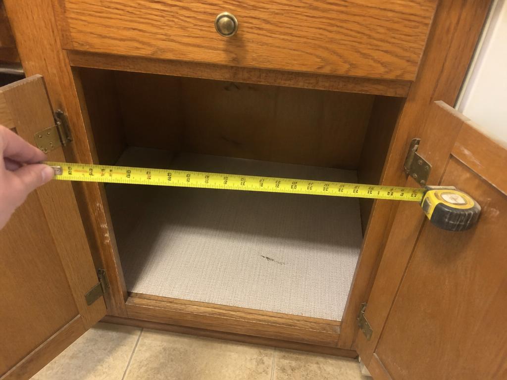 A tape measure stretched across a kitchen cabinet opening