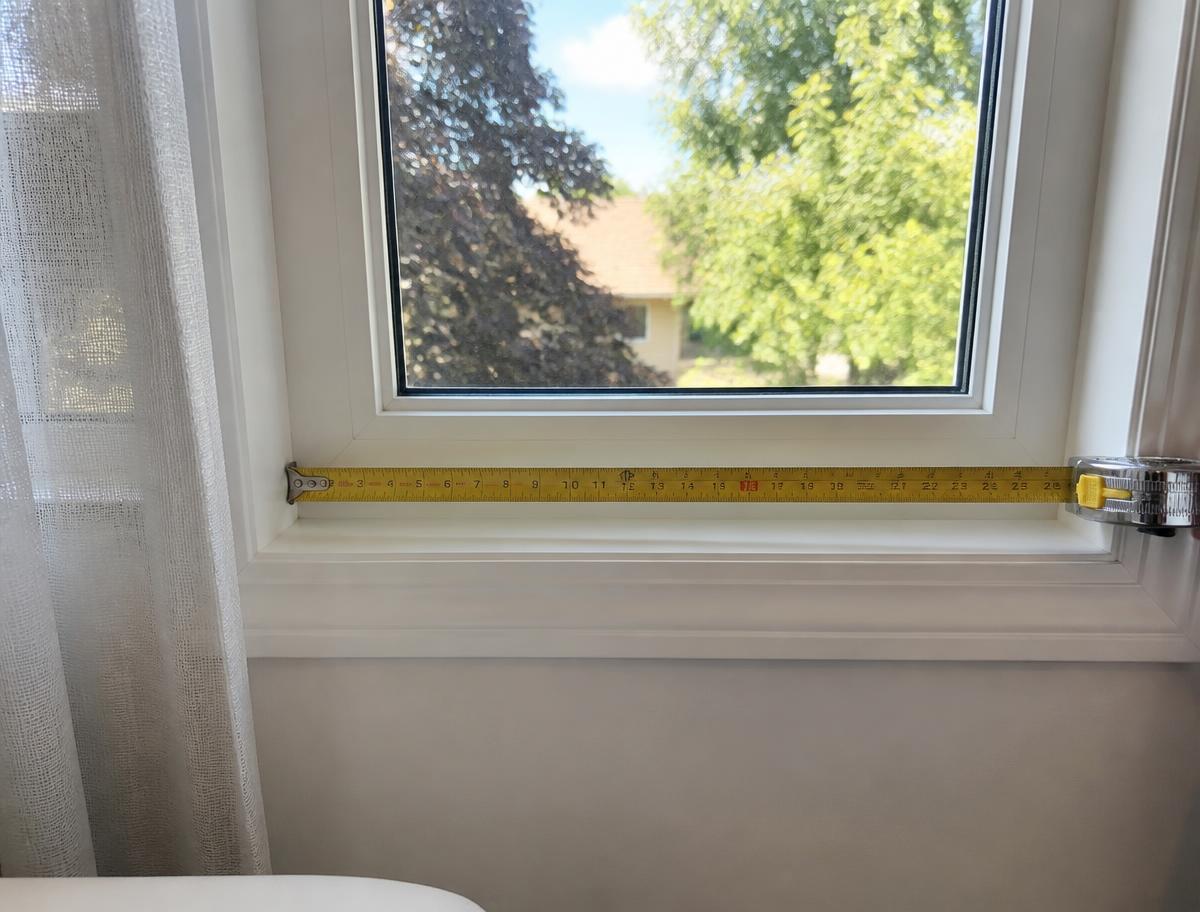 A tape measure stretched across the inside width of a living room window